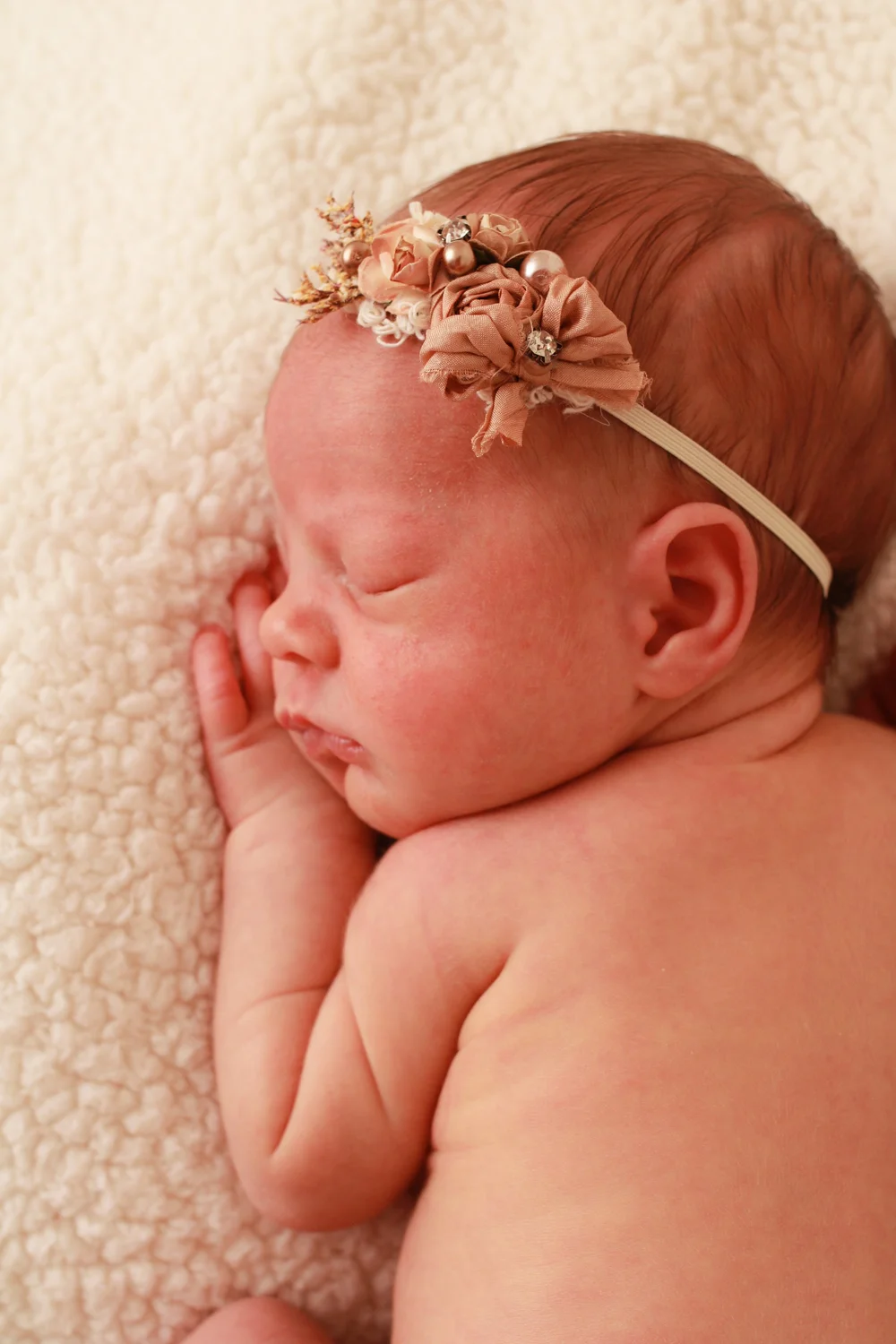 Profile portrait of a sleeping newborn baby girl wearing a delicate floral headband — serving Merrick, NY families