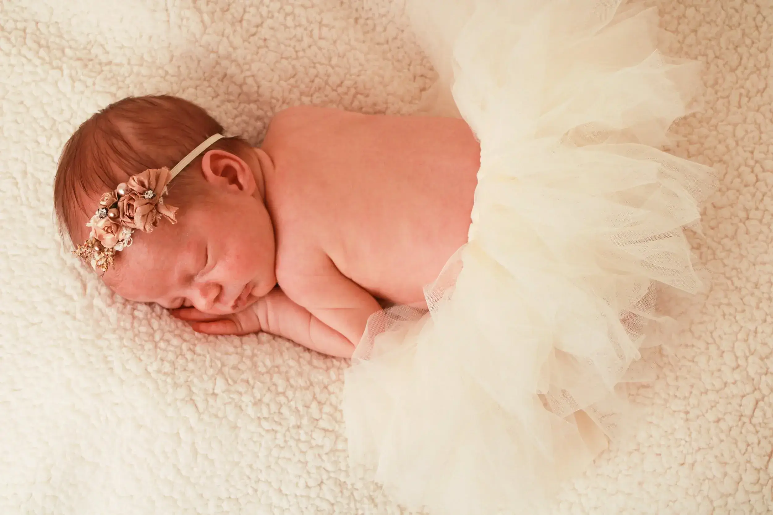 Newborn baby girl wearing an ivory tutu and floral headband — serving Lawrence, NY families